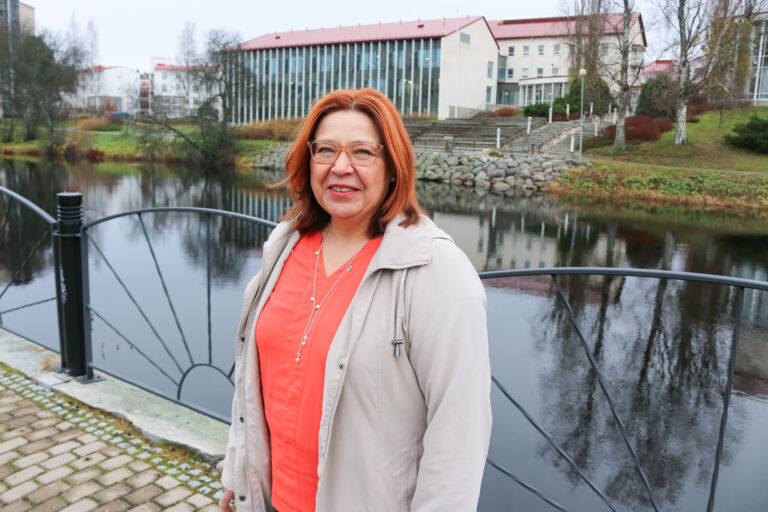 Nainen seisoo rannassa taustallaan joki.