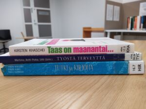 Book spine boetry in finnish: Taas on maanantai, Työstä terveyttä, Tutki ja kirjoita.