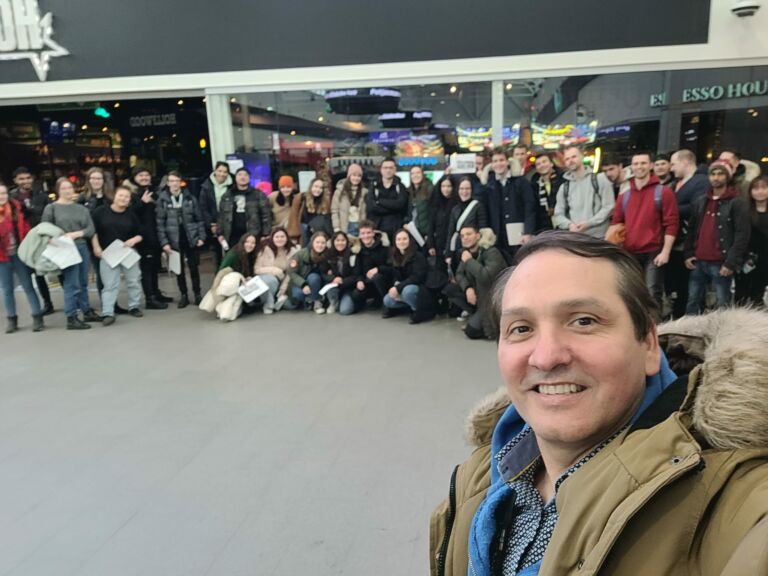 A man takes a selfie in the mall with large group of students background