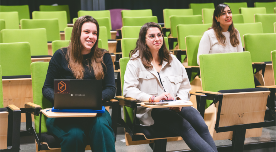 Three students sitting in an auditorium.