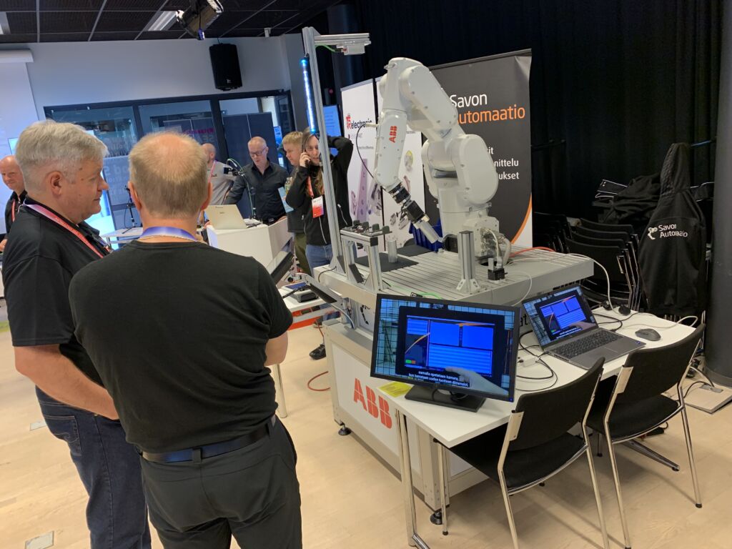 Kaksi miestä seuraa teollisuusrobotin toimintaa.