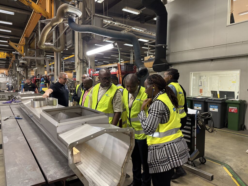 A group of people with yellow vests in factory.