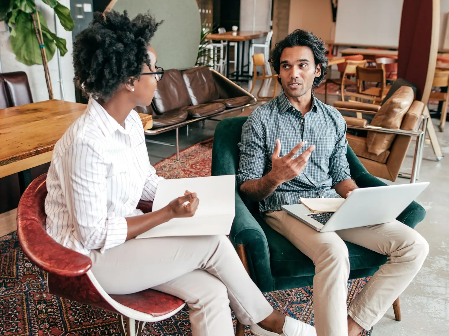 Two people are sitting together in a state-of-the-art computer office, reviewing together the website code they are developing