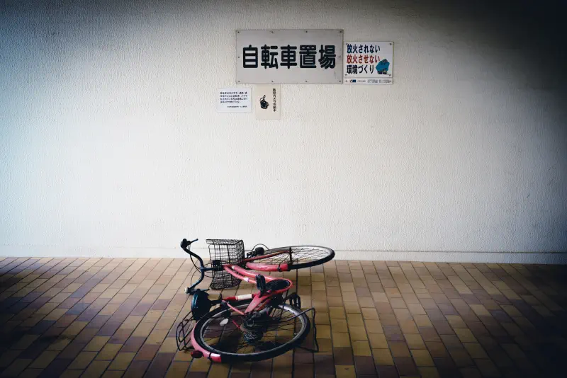 壁際の駐輪場に横たわる赤い自転車