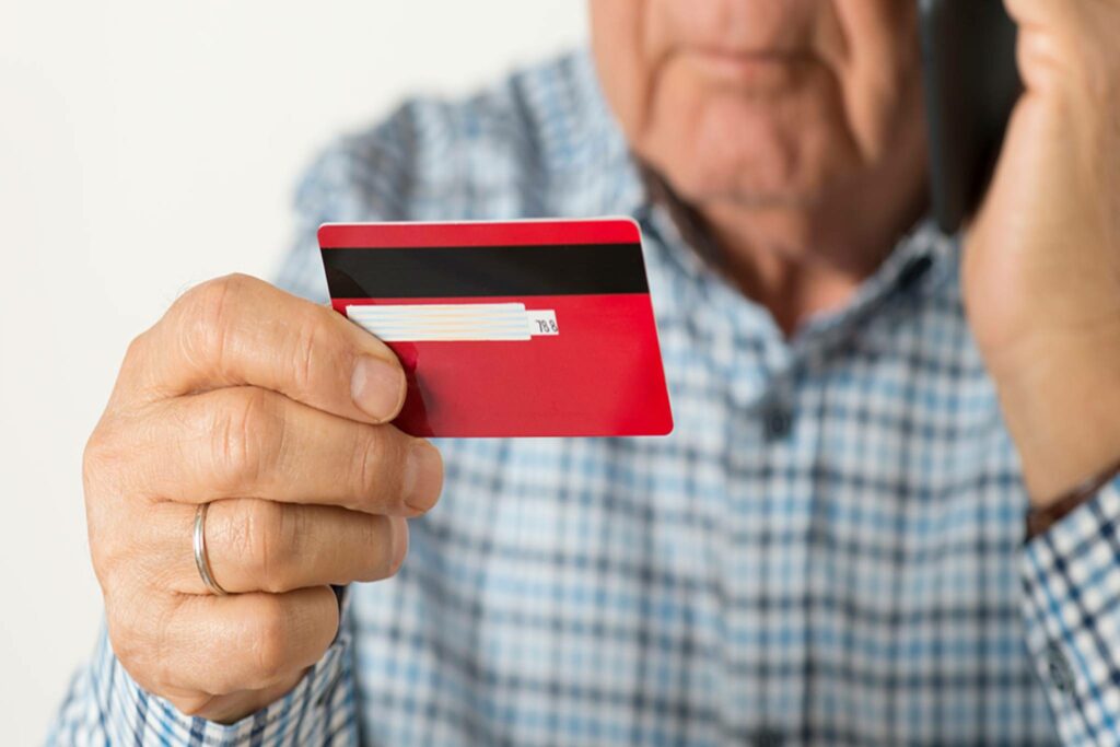 Senior man holding credit card and talking on the phone