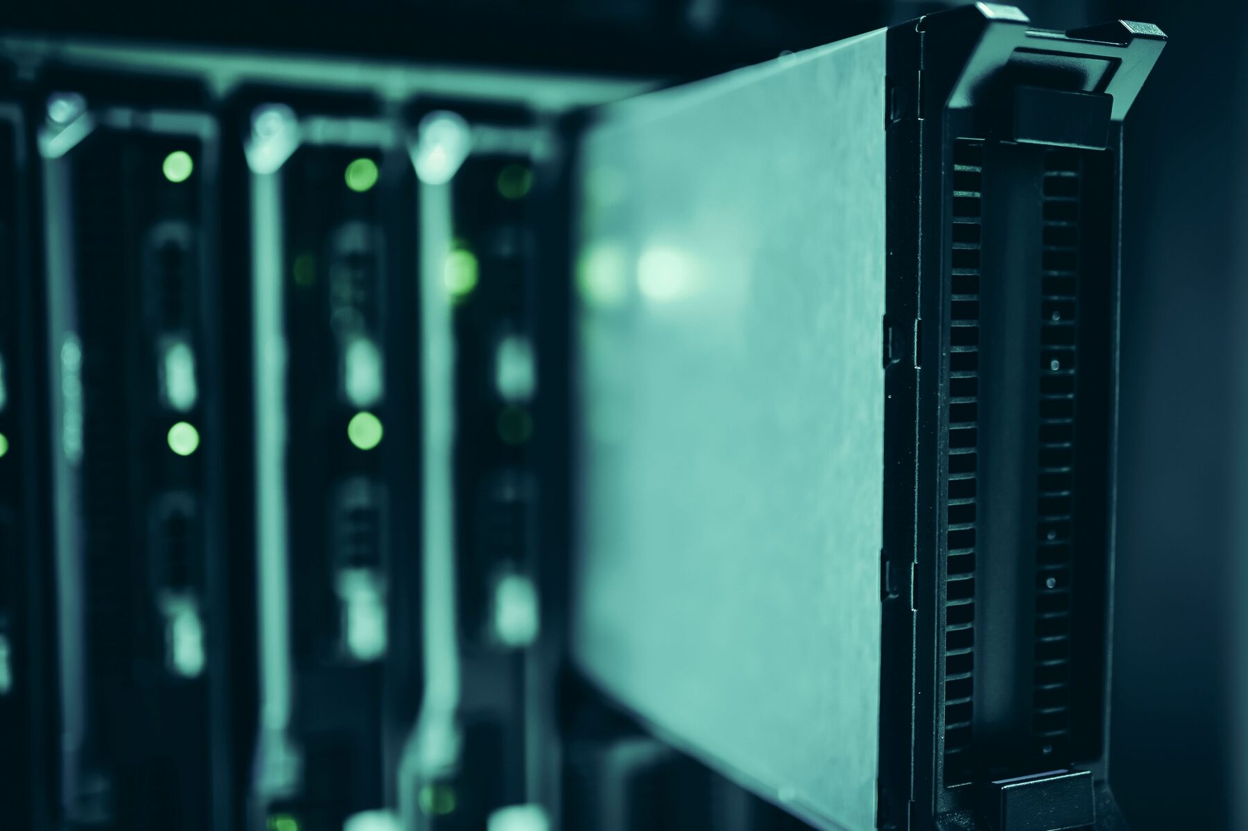 Rows of dark server racks in a data hall, front panels lit by small blue status lights
