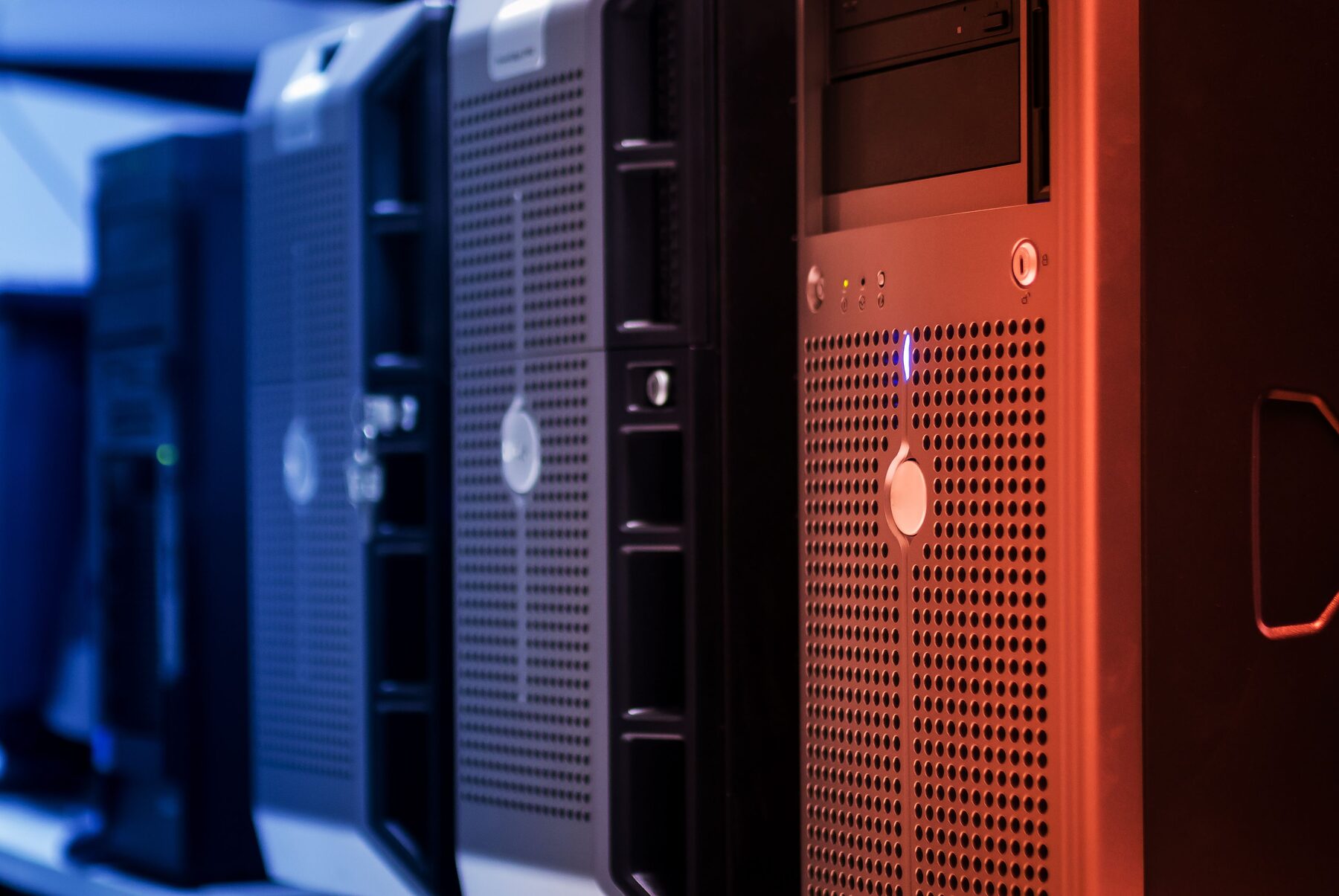A close row of tower servers photographed head-on under blue and red lighting