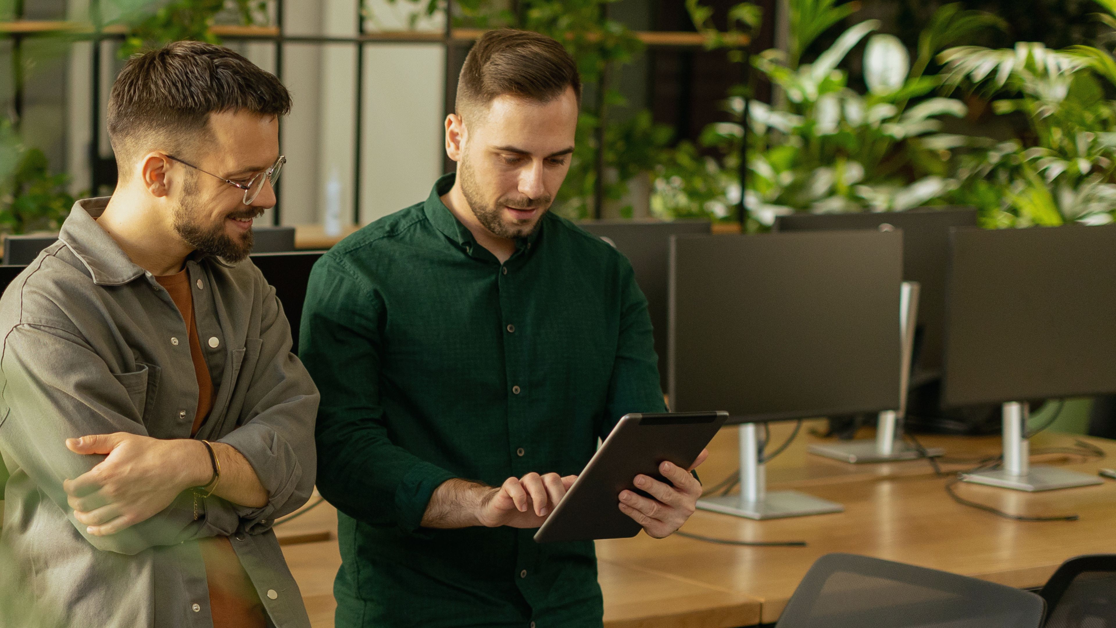 two men speaking, staring at an ipad