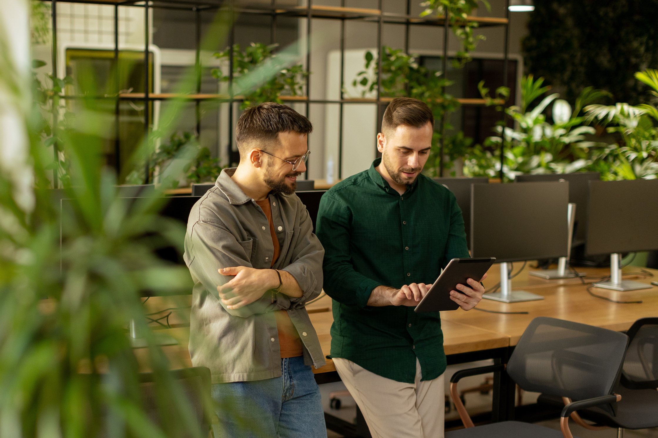 two men speaking, staring at an ipad