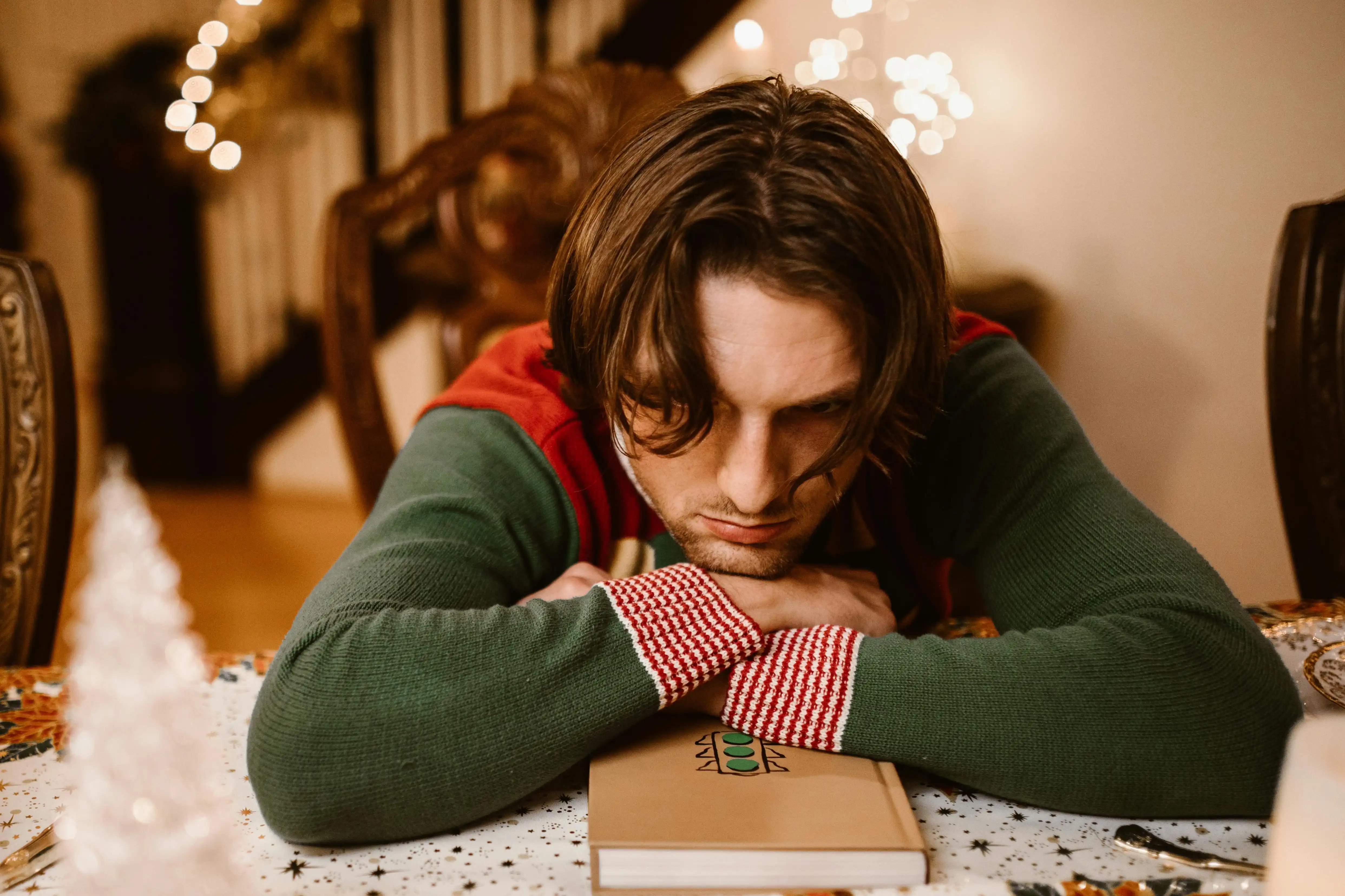 A man in a Christmas-themed sweater feeling sad.