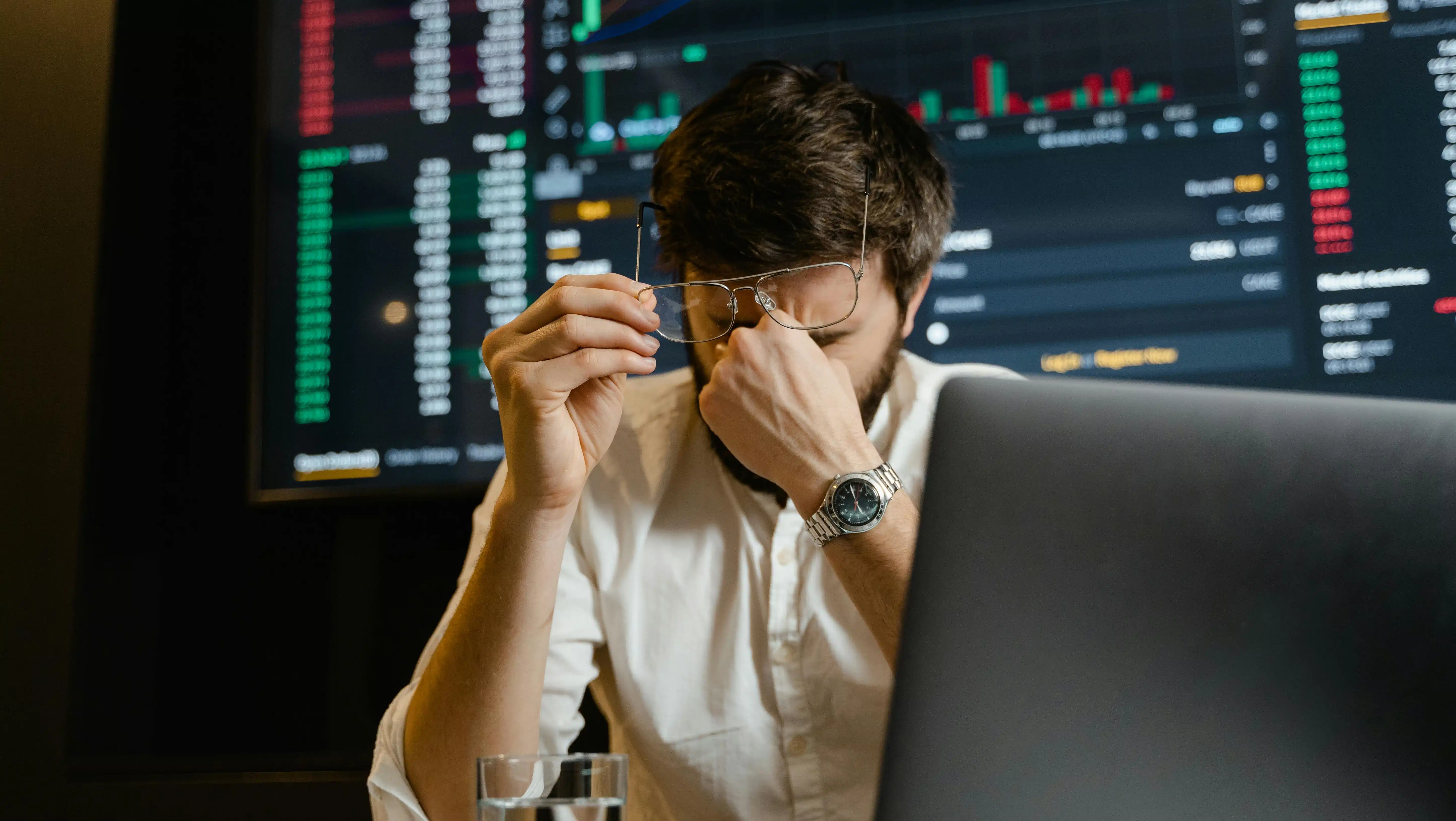 A man looking stressed while using a black laptop