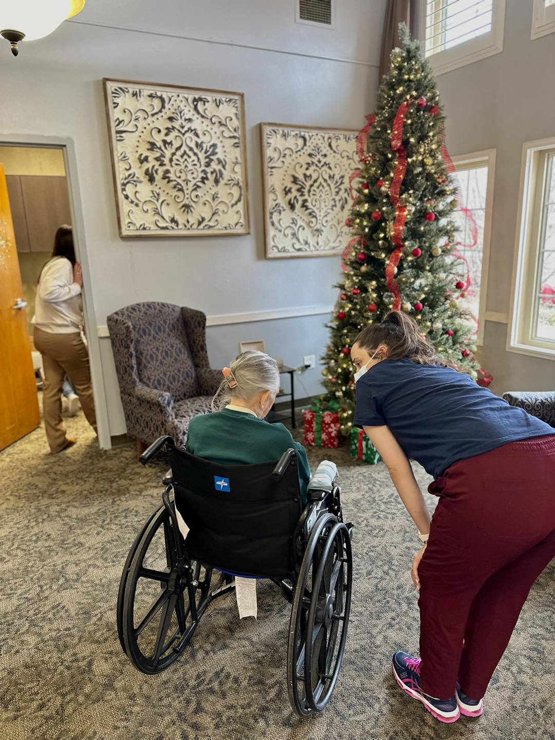 One of our rehab team members taking the time to talk with a skilled patient in front of the Christmas tree 