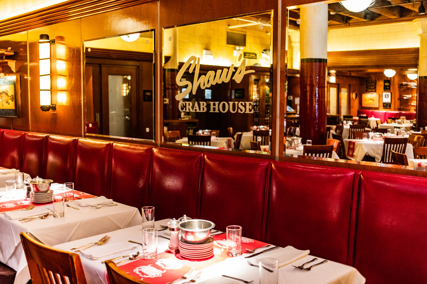 shaws dining room focused on a mirror with lettering that reads shaws crabhouse above a red banquet with white tablecloth tables