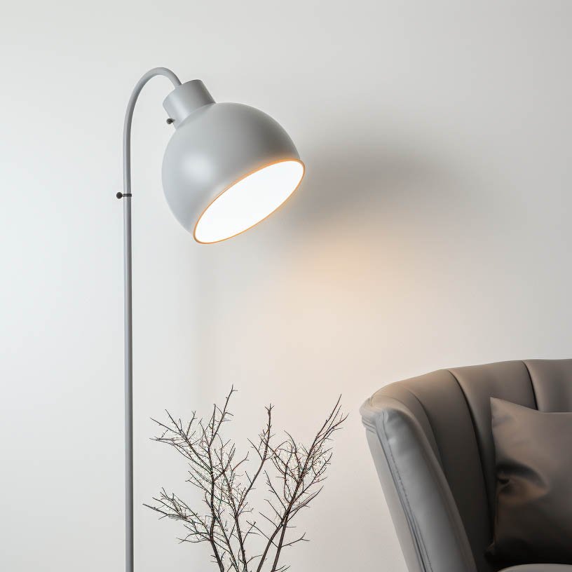 Moderne Stehlampe mit schickem, grauem Lampenschirm und elegantem Design, neben einem stilvollen Sessel sowie einer minimalistischen Dekoration mit einem trockenen Zweig, auf einem hellen Hintergrund.