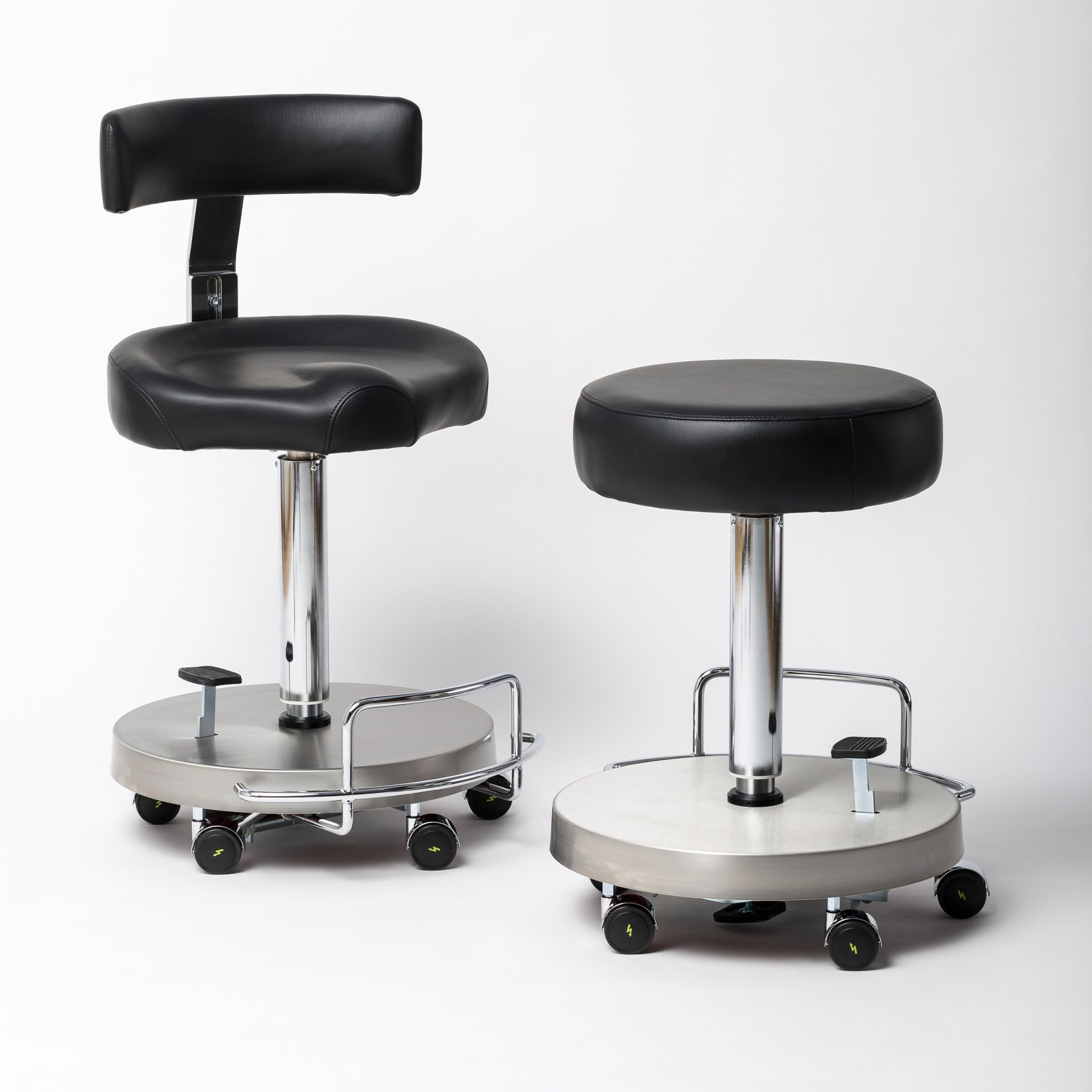 Zwei moderne Drehhocker mit schwarzem Kunstlederbezug, einer mit Rückenlehne und der andere ohne, beide mit stabiler chromfarbener Basis und Rollen für einfache Mobilität.