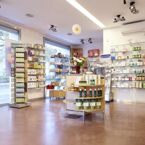 Innenansicht eines Geschäftes für Gesundheits- und Schönheitsprodukte mit Regalen voller Tees, Nahrungsergänzungsmittel und Kosmetika. Die hellen Wände und das moderne Design schaffen eine einladende Atmosphäre. Im Mittelpunkt steht ein runder Tisch mit verschiedenen Pflegeprodukten.