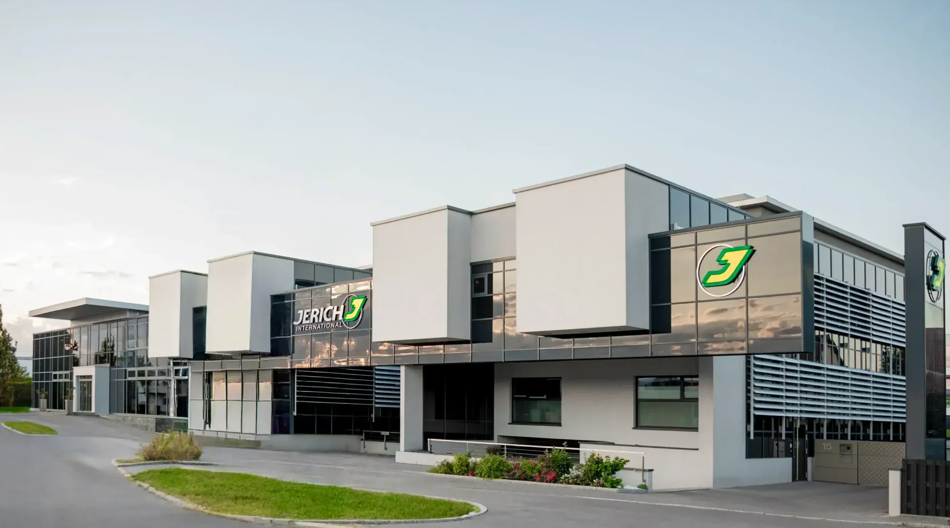 Modern office buildings with the sign “Jerich” in a commercial area, surrounded by green spaces and a parking lot.