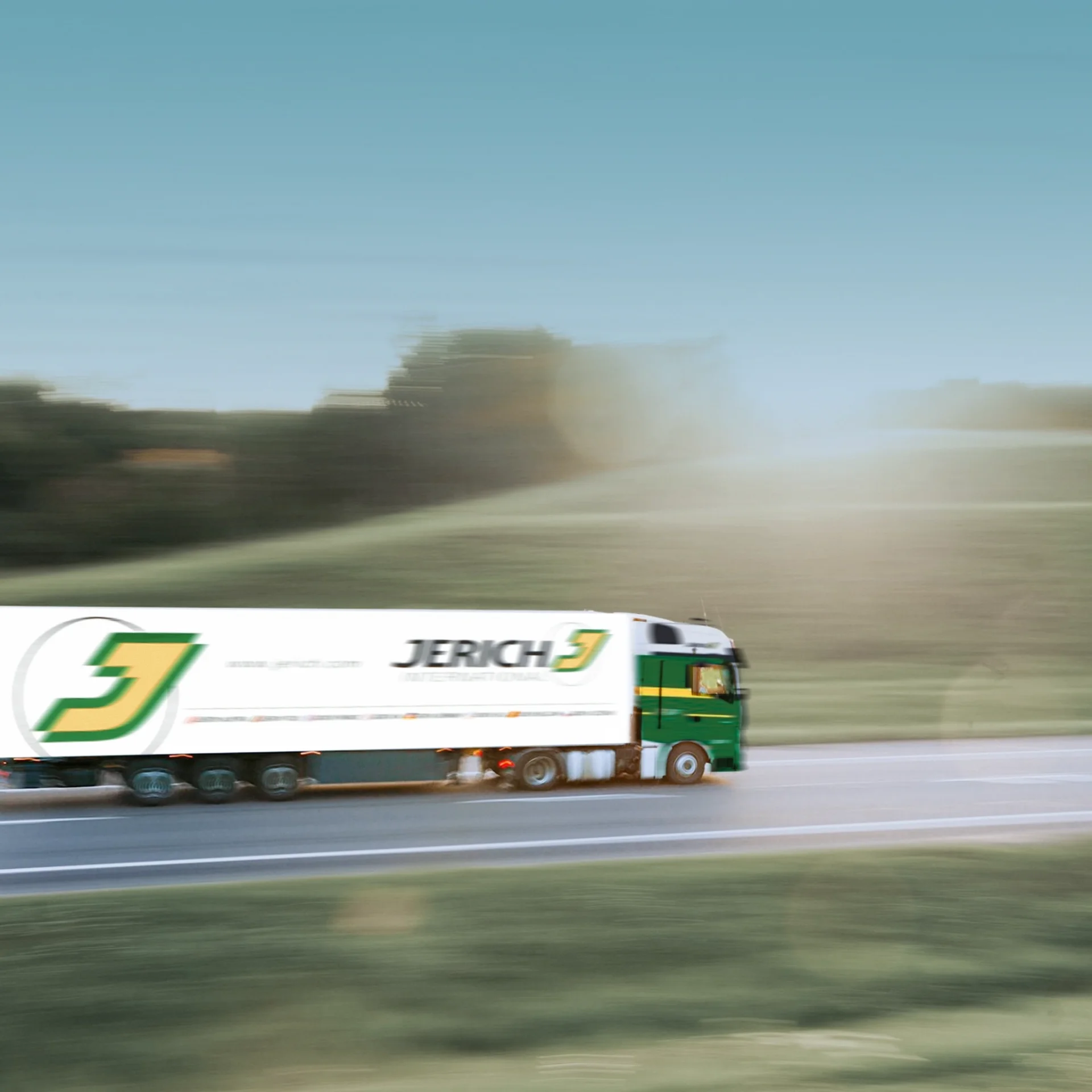 Ein schnell fahrender Lastwagen mit dem Logo von Jerich auf einer Straße, umgeben von grünen Hügeln und einer klaren blauen Himmel.