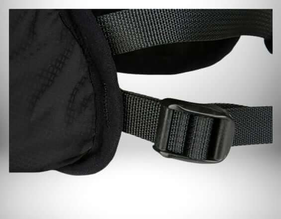 Un gros plan d'un sac à dos d'hydratation noir. L'image se concentre sur une section du sac, qui comprend une sangle et une boucle. Le sac porte une texture alvéolaire.