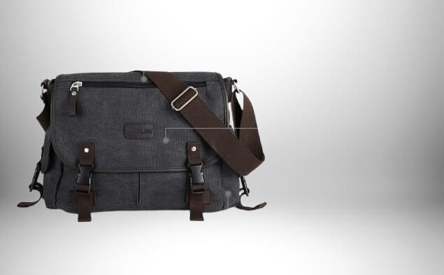 Un sac bandoulière en toile homme noir avec des sangles en cuir marron et des boucles métalliques sur un fond blanc dégradé.