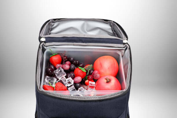 Sac à dos glacière noir ouvert montrant un récipient rempli de fruits frais