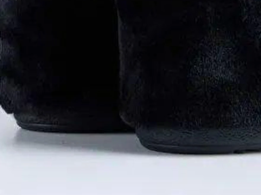 Soft, low resolution close-up of black faux fur boots and their soles