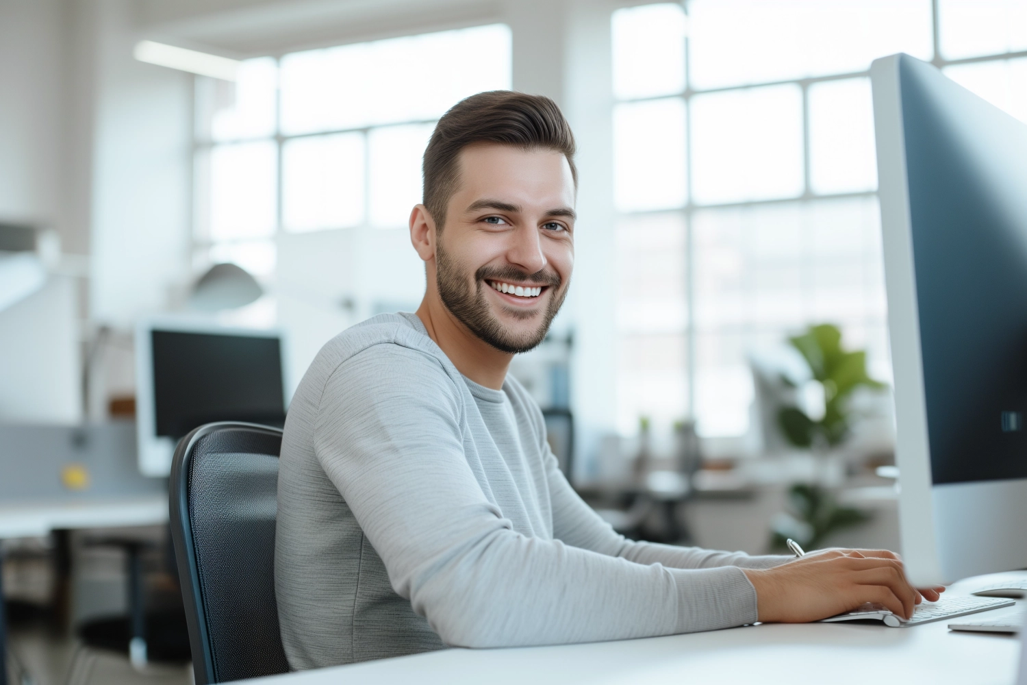 Portrait of Enthusiastic white man Working on Computer in a Modern Bright Office. Confident Human Resources Agent Smiling Happily While Collaborating Online with Colleagues