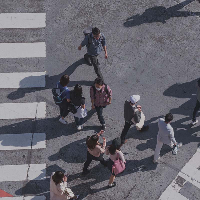 Photograph from above of people walking on a street with painted crosswalks