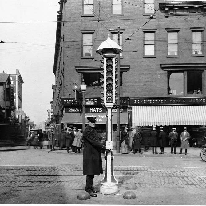An operator stands beside an early General Electric traffic signal