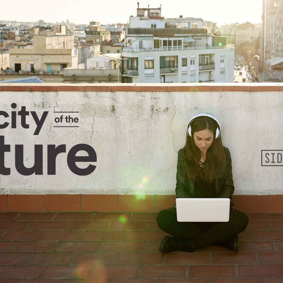 A woman sits outside working on a laptop with headphones on