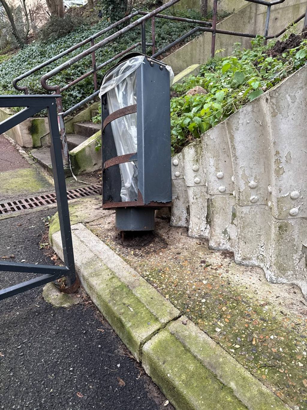 Poubelle cassée risquant de se détacher.