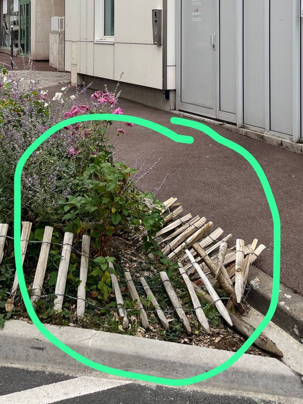 Palissade en bois devant crèche endommagée.