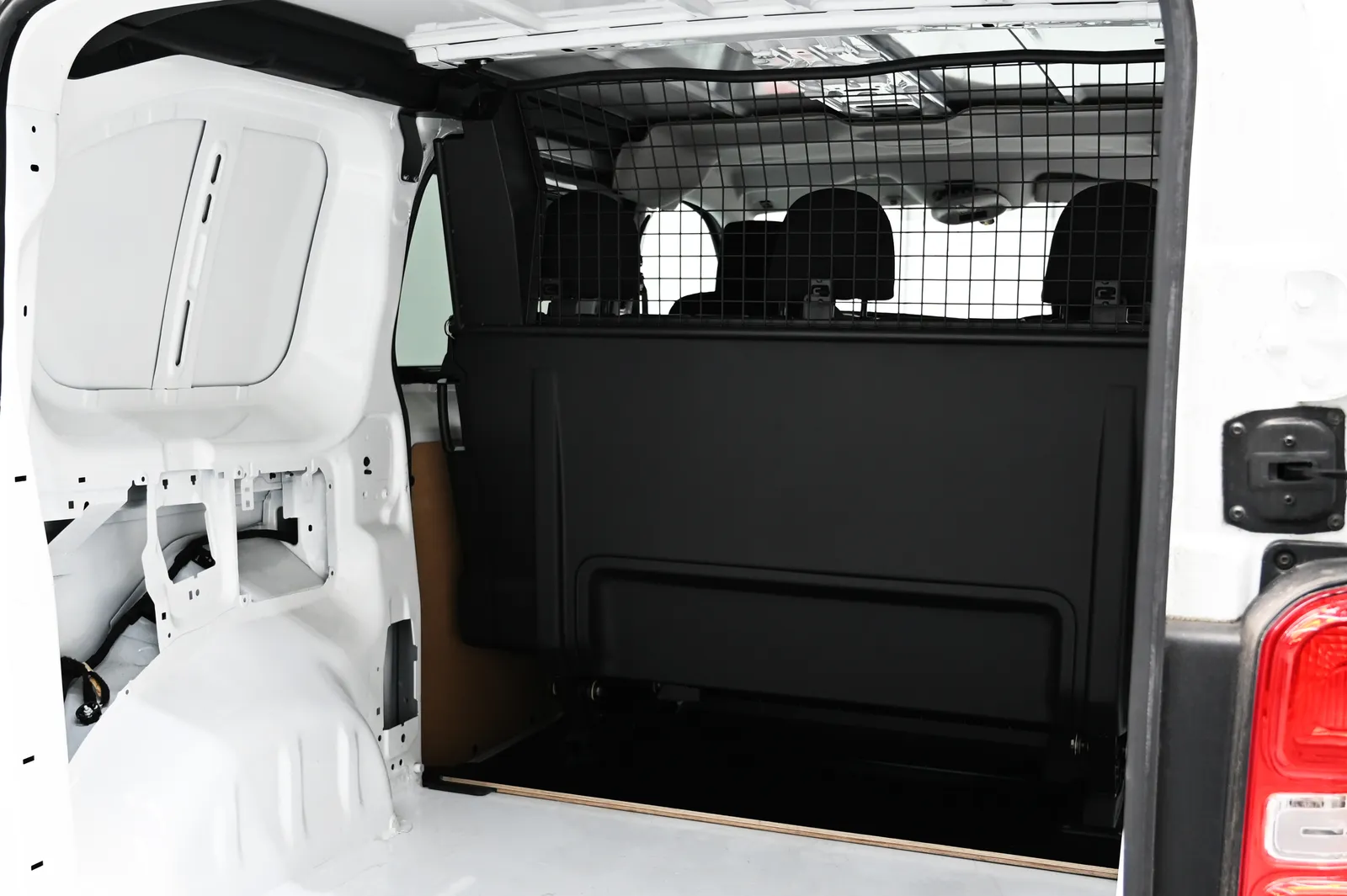Interno di un furgone bianco, mostrando l'ampio vano di carico, la paratia di sicurezza e la griglia protettiva.