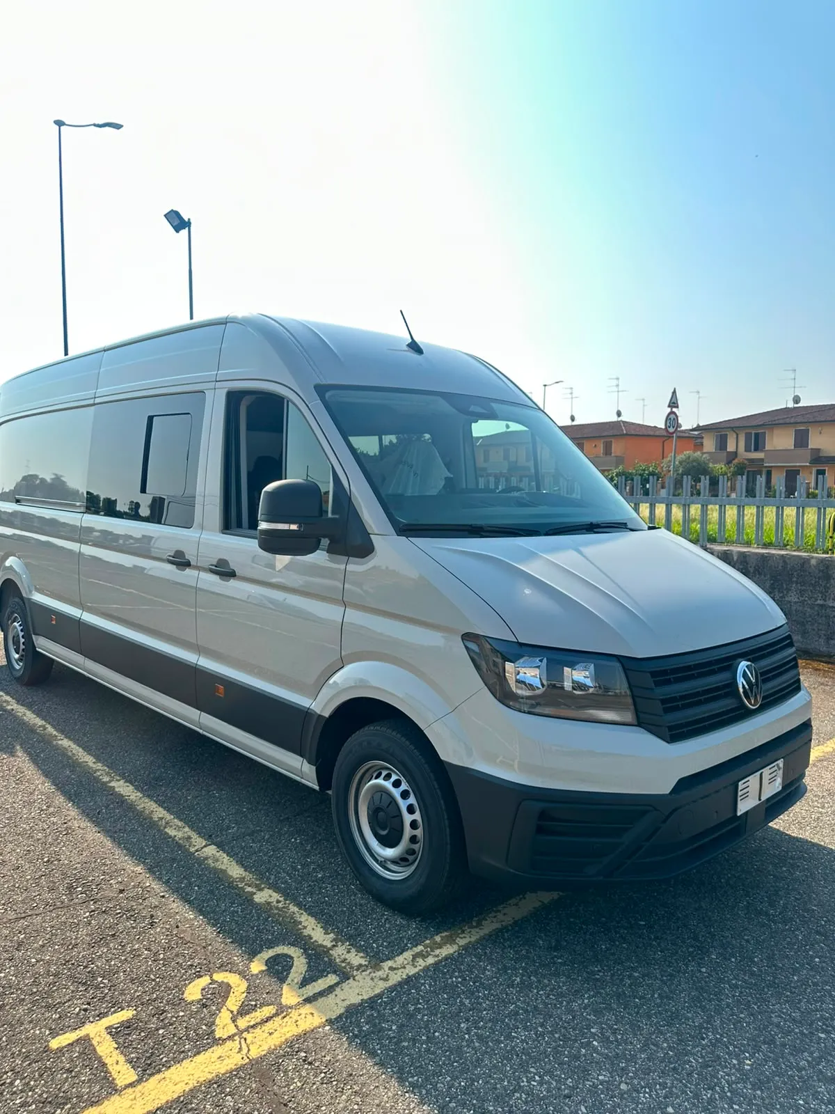Nuovo Volkswagen Crafter grigio chiaro in un parcheggio assolato.