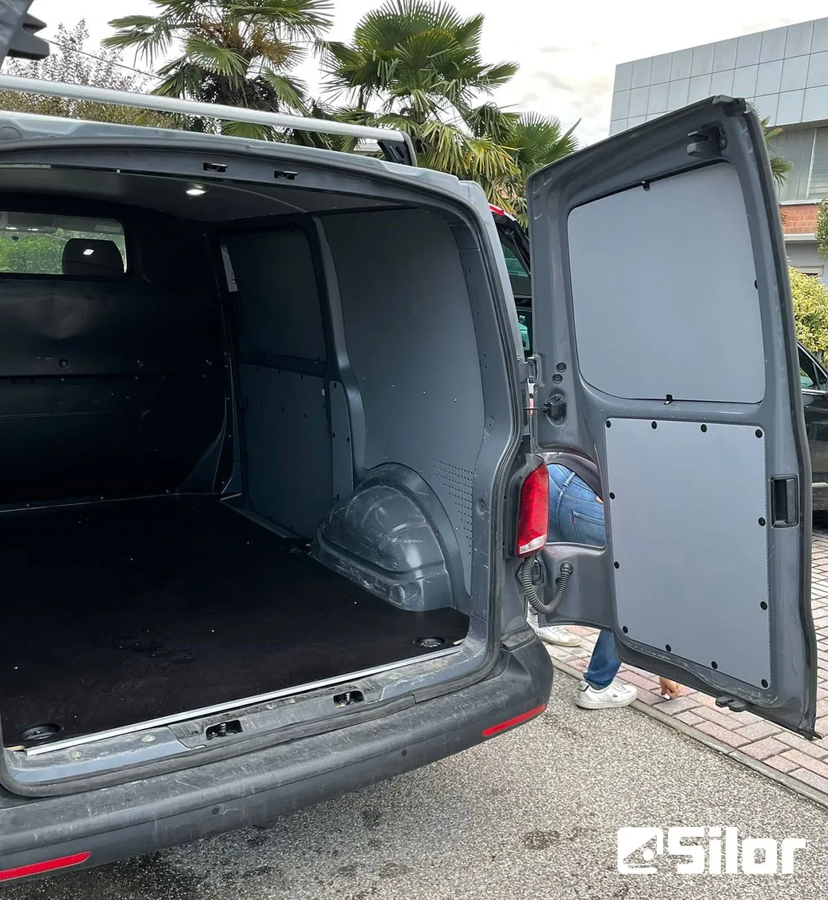 Porte posteriori del furgone aperte, che rivelano lo spazio di carico rivestito.