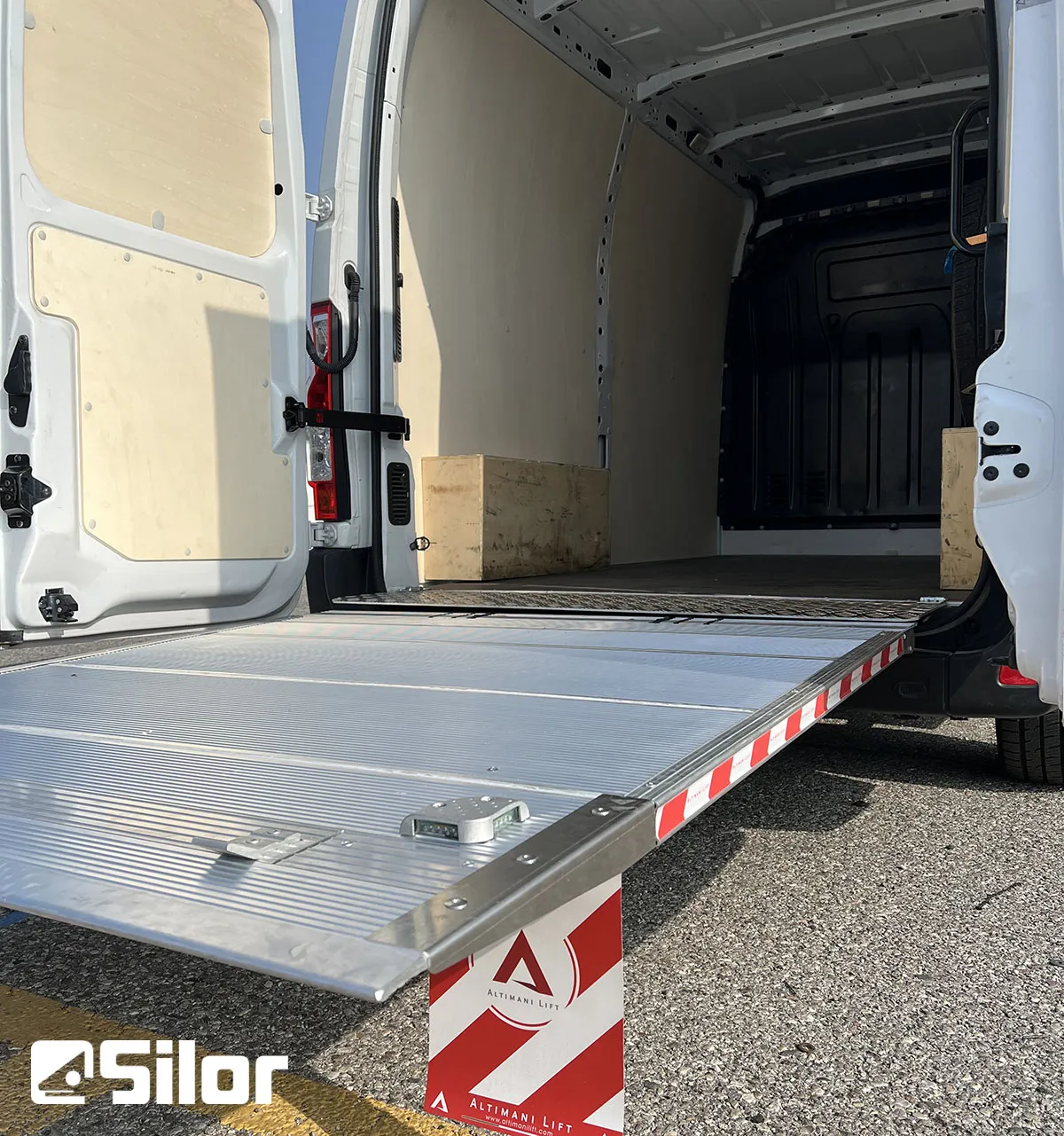 Interni di un furgone bianco con sponda montacarichi aperta.