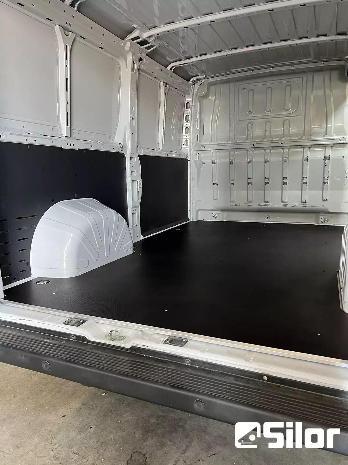 Interno di un furgone bianco con pavimento nero.