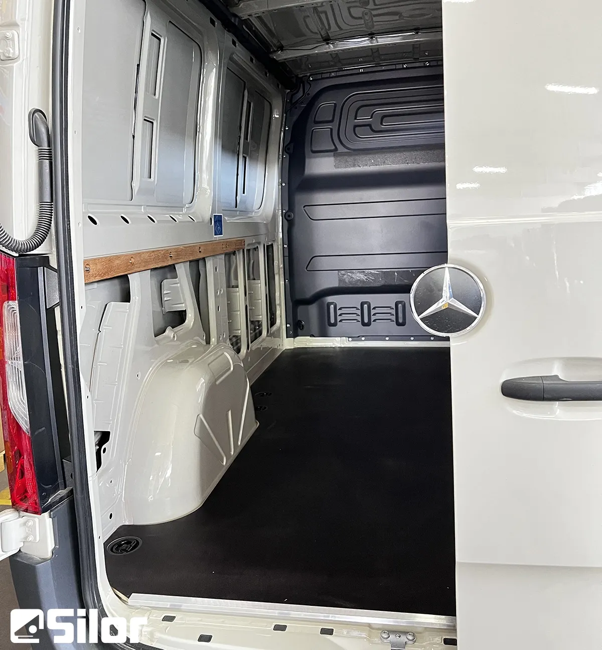 Interno di un furgone bianco Mercedes-Benz con pavimento nero.