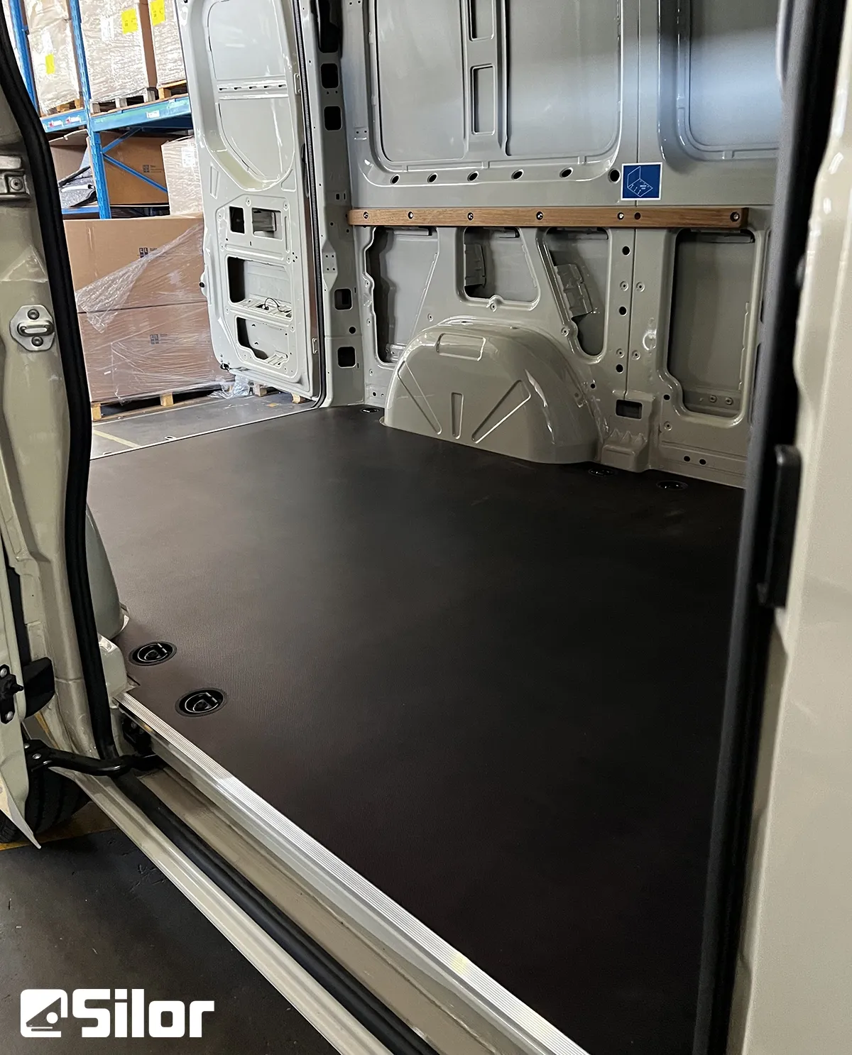 Interno di un furgone da carico bianco con pavimento nero.