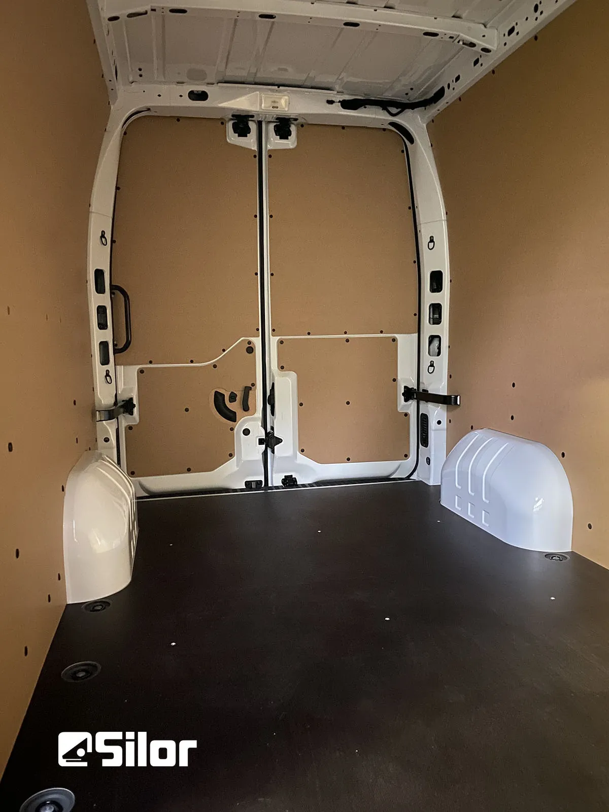 Interni di un furgone commerciale con rivestimento in legno e pavimento nero.
