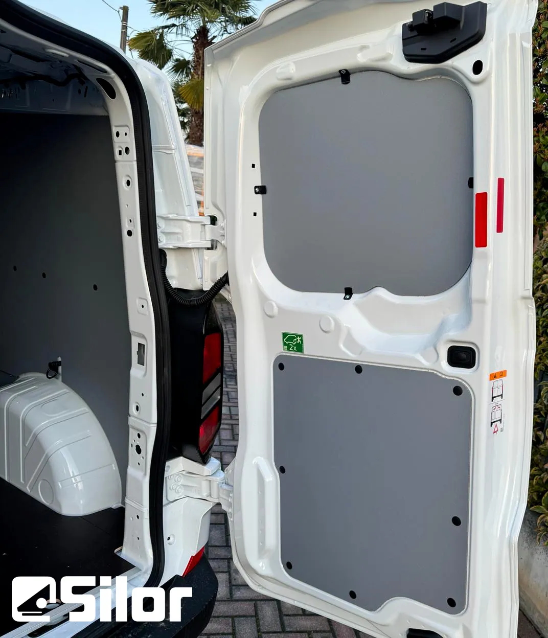 Interno di un furgone bianco con le portiere posteriori aperte.