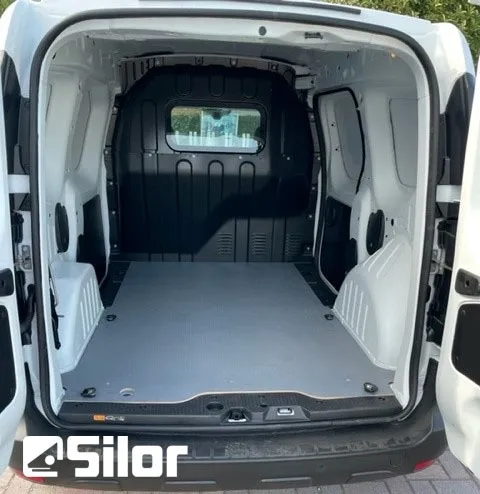 Interno di un furgone bianco con pavimento grigio.
