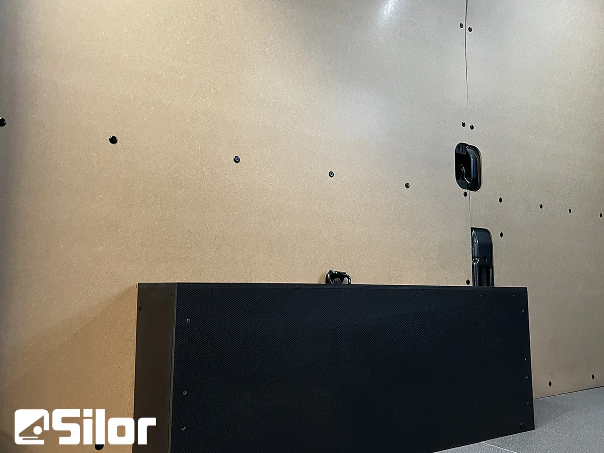 Interni di un furgone rivestito con pannelli in legno, con un mobile nero e il logo Silor.