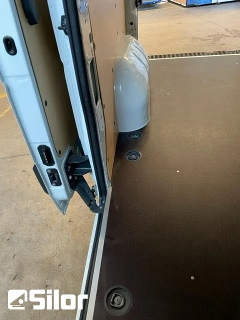Interno di un furgone bianco con porte aperte e pavimento nero.
