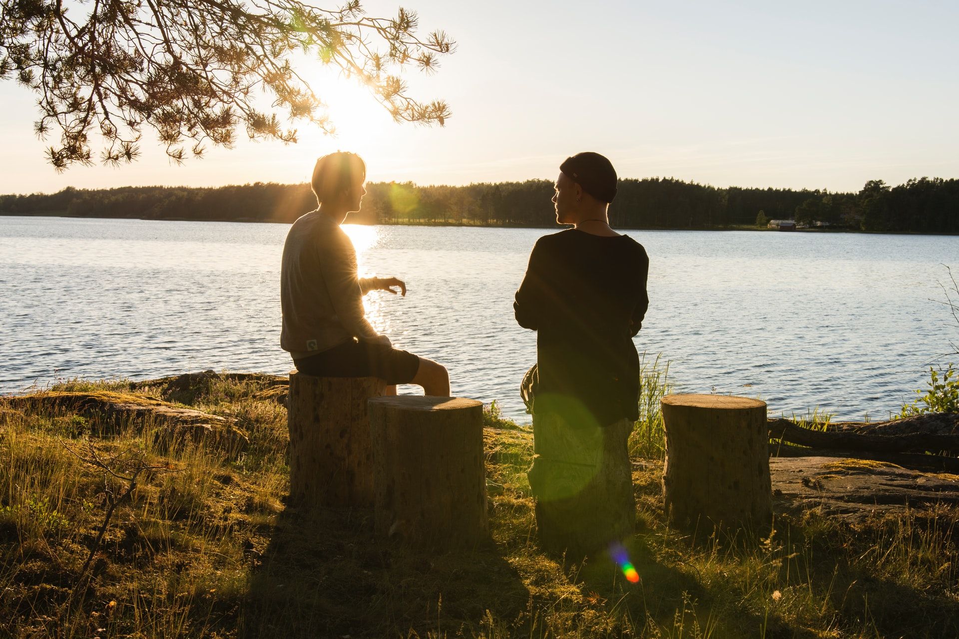 Kaksi nuorta miestä keskustelee rannalla