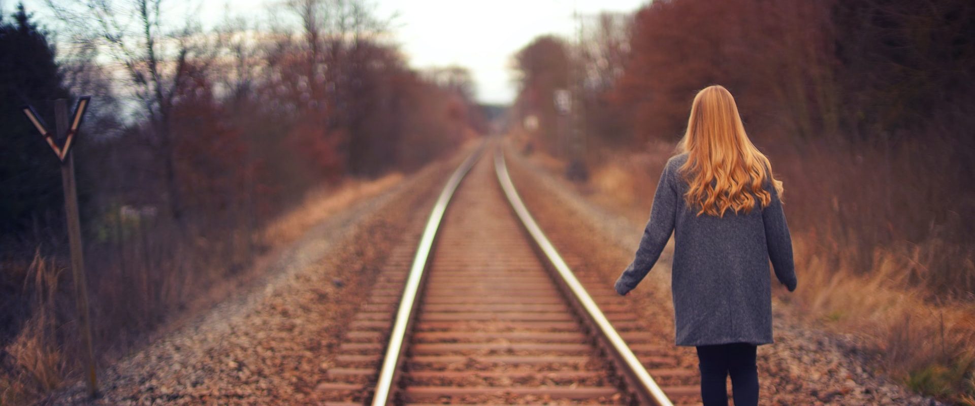Nainen kävelee junaradan viertä