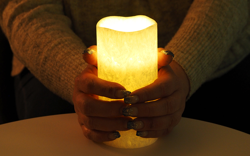 Naisen kädet pitelevät kynttilää