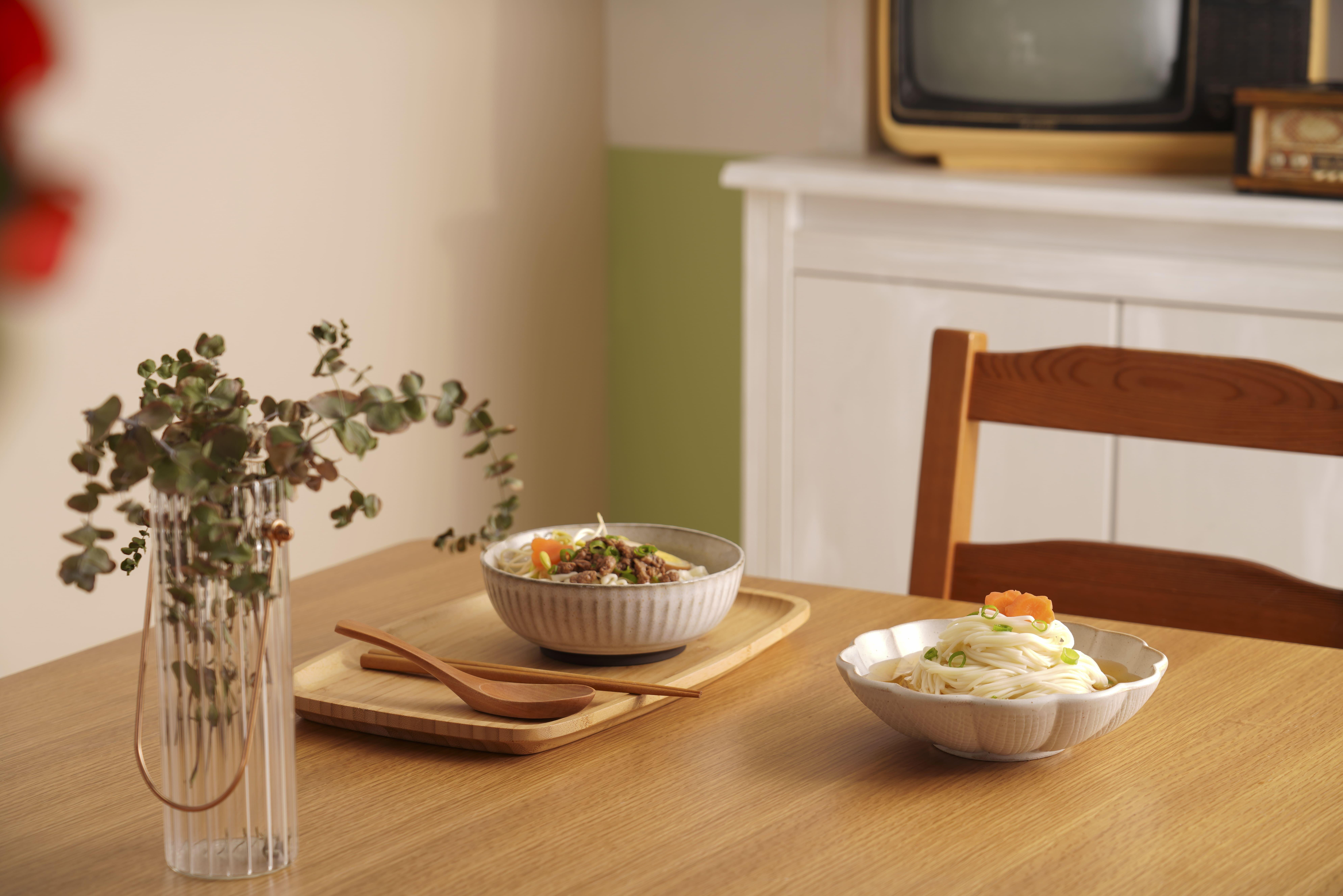 Two bowls of Taiwan ramen noodles served on a wooden table in a cozy home kitchen.