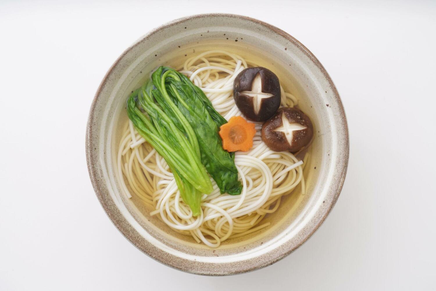 一碗清湯麵，搭配波菜、香菇與胡蘿蔔片，湯色清透、風味清爽。