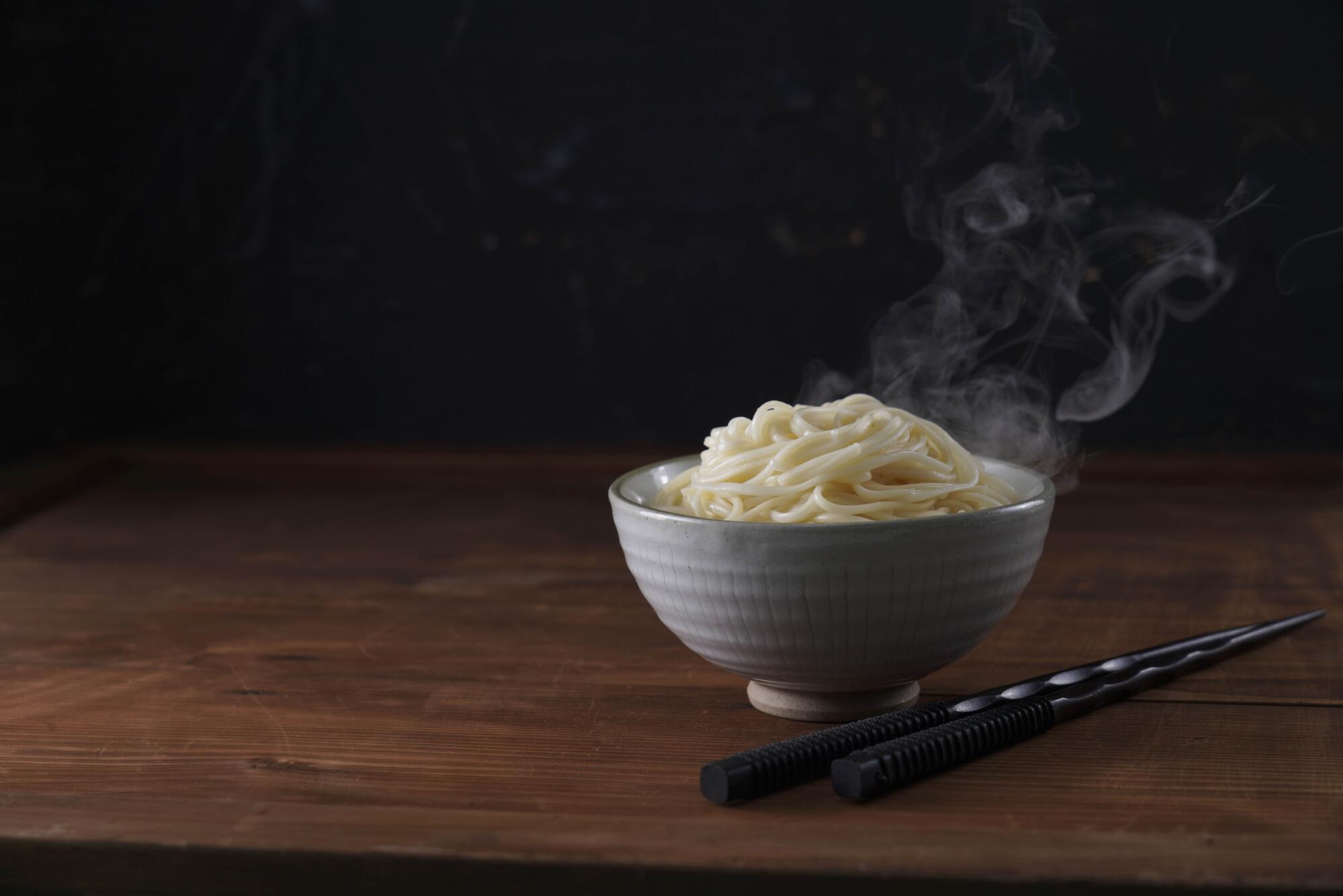 陶瓷碗中盛著剛煮好的熱湯麵，蒸氣裊裊上升，展現Q彈口感與純淨麵香。